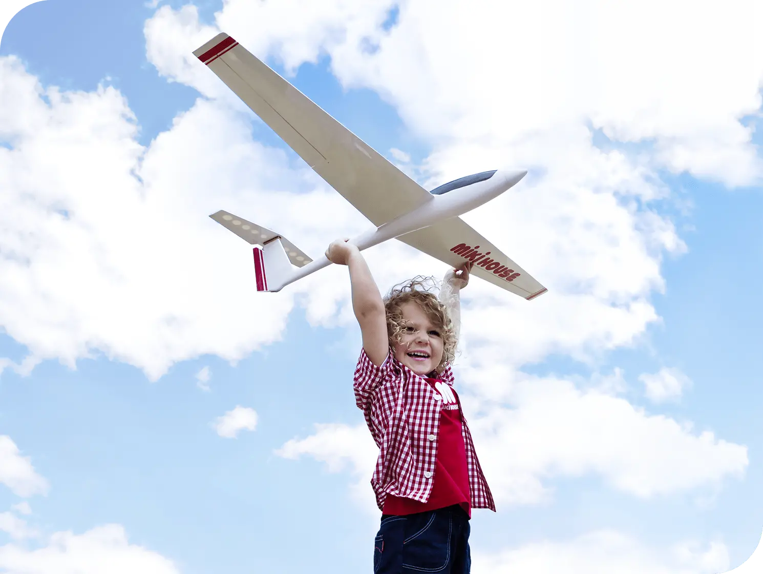 おもちゃの飛行機を持って空に向かって笑う子ども