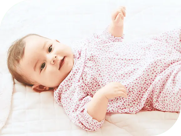 ベッドに寝転んで笑っている赤ちゃん