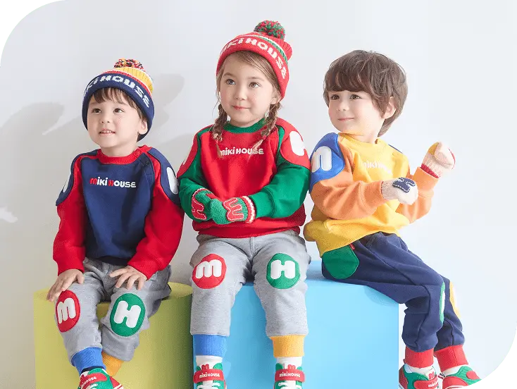 カラフルな服を着て座っている三人の子ども