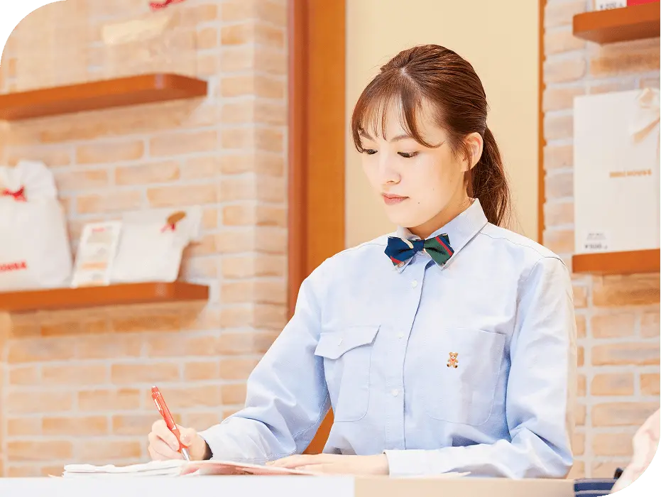 ミキハウスの店舗でメモを取りながら業務に取り組むM.H.さん