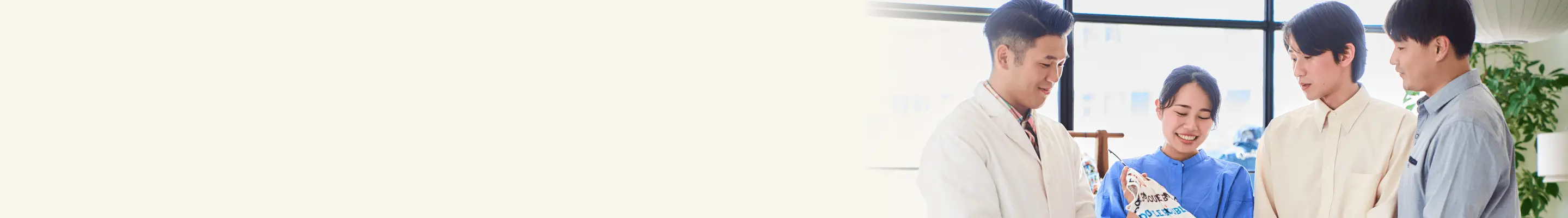 カラフルなTシャツを着た5人の若いスタッフが笑顔でガッツポーズをしている様子