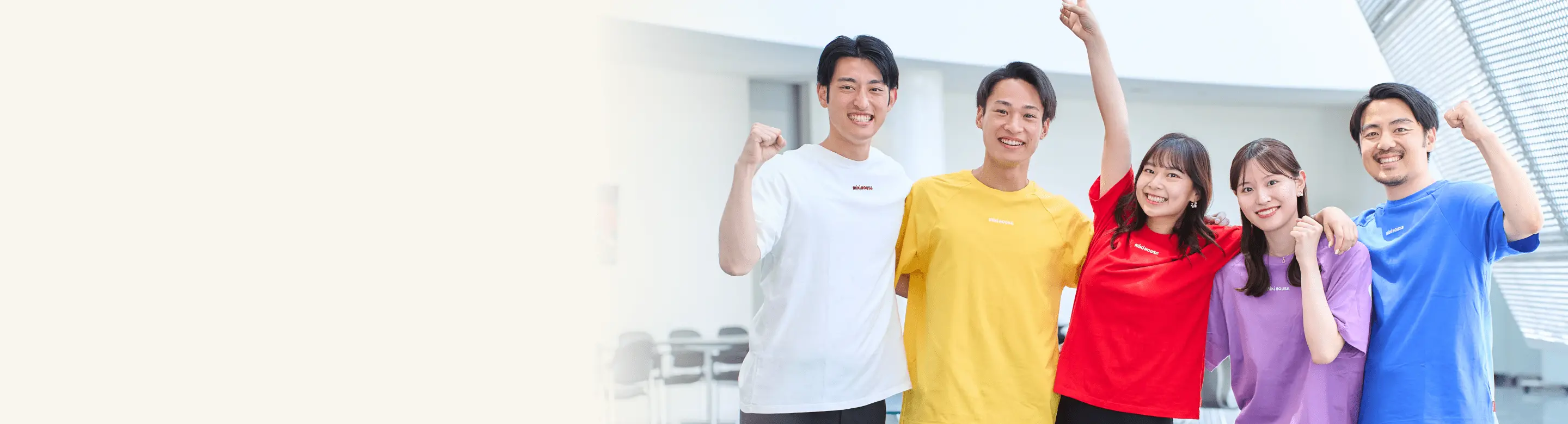 カラフルなTシャツを着た5人の若いスタッフが笑顔でガッツポーズをしている様子