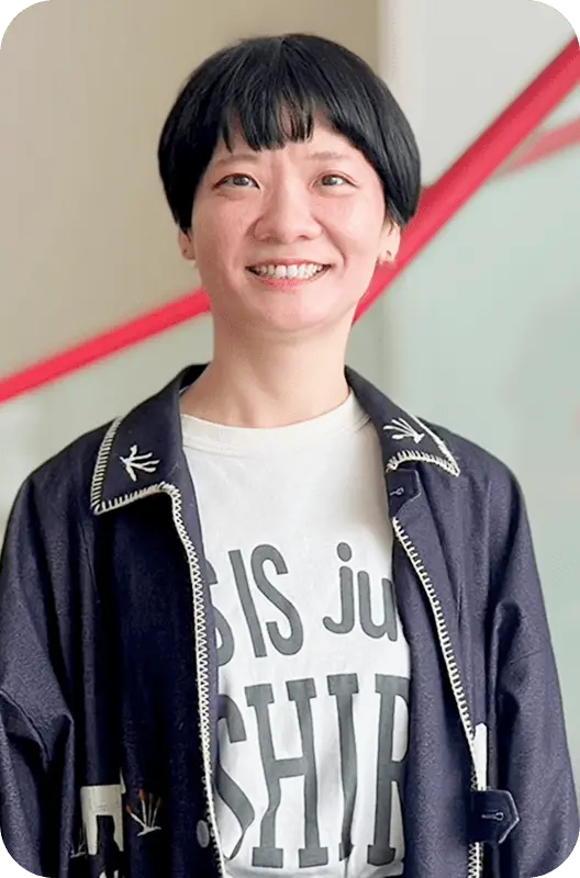 黒髪ショートヘアで笑顔のW.Jさんが黒いジャケットと白いTシャツを着用したポートレート